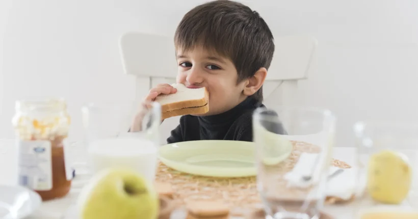 front-view-kid-eating-sandwich-table