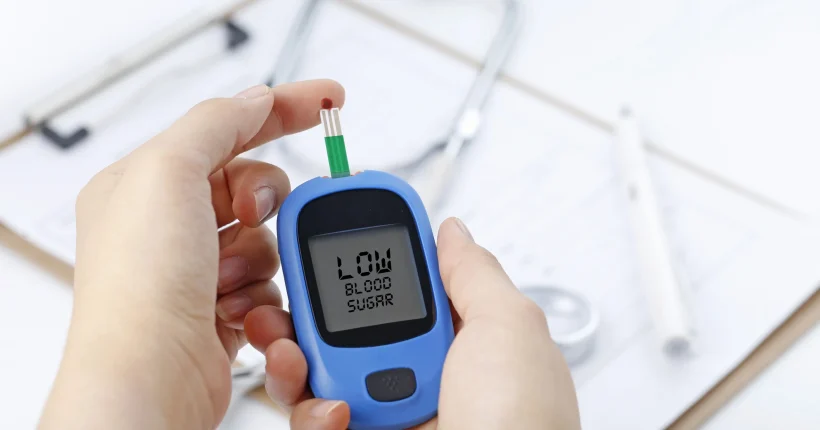 hand-holding-blood-glucose-meter-measuring-blood-sugar-background-is-stethoscope-chart-file